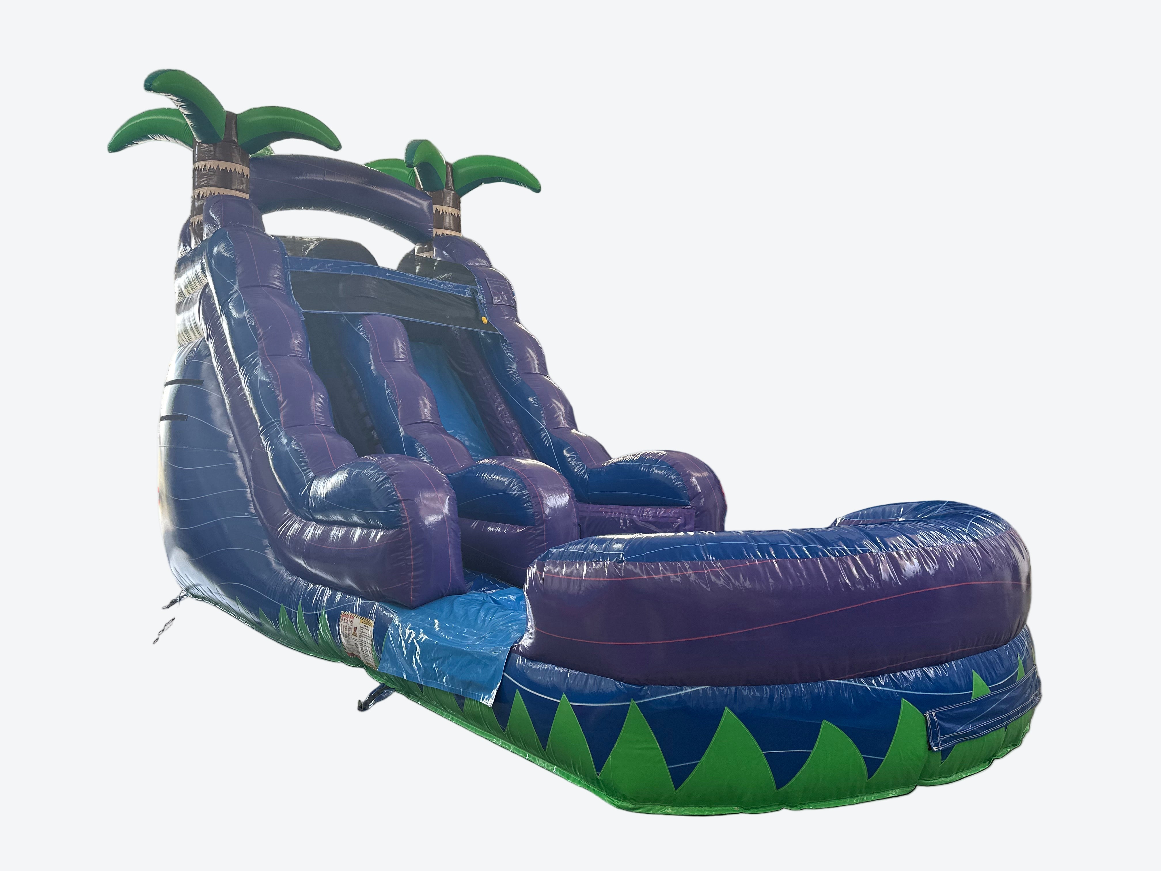 Large inflatable water slide with palm tree design in an indoor warehouse setting