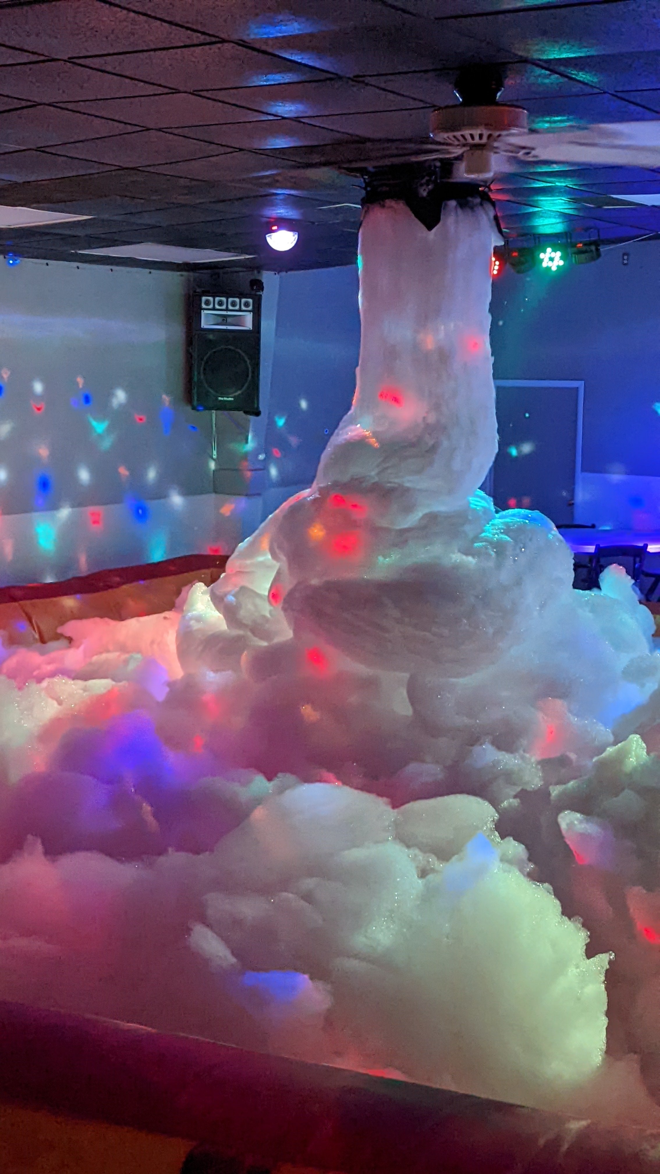 Party foam on a dance floor beneath colorful lights